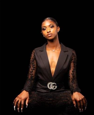 Masai Russell is sitting on a stool with a black background