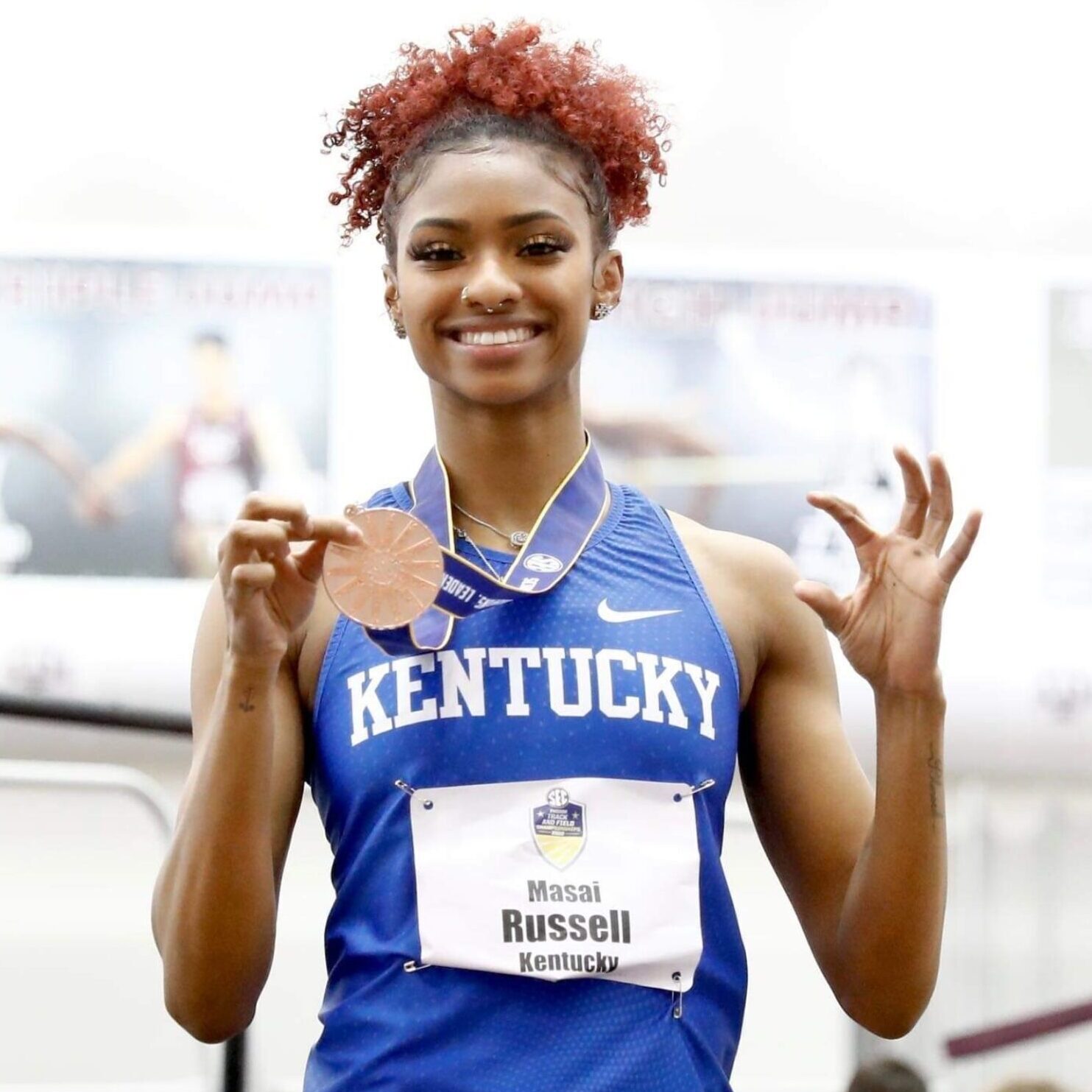 Smiling athlete in Kentucky uniform holding medal